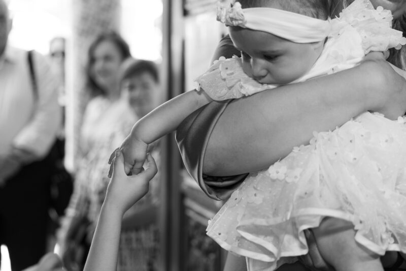 Τρυφερή ασπρόμαυρη στιγμή με βρέφος κατά τη διάρκεια της βάπτισης